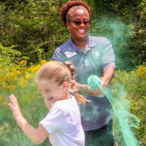 woman sprays green dust a kid during color run