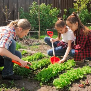 Photo of two teenage girls with mother working in backyard garden