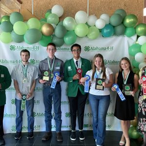 Alabama 4-H members holding ribbons and awards they won at competitive events day.