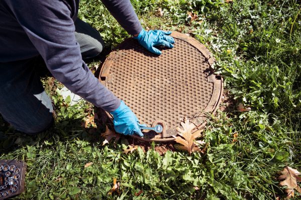 A worker opening the lid to a septic tank system.