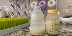 pumped breast milk in a bottle beside a baby bottle
