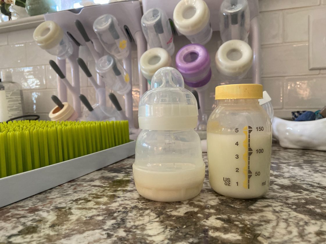 pumped breast milk in a bottle beside a baby bottle