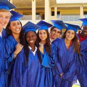 A group of high-school graduates in blue caps and gowns.