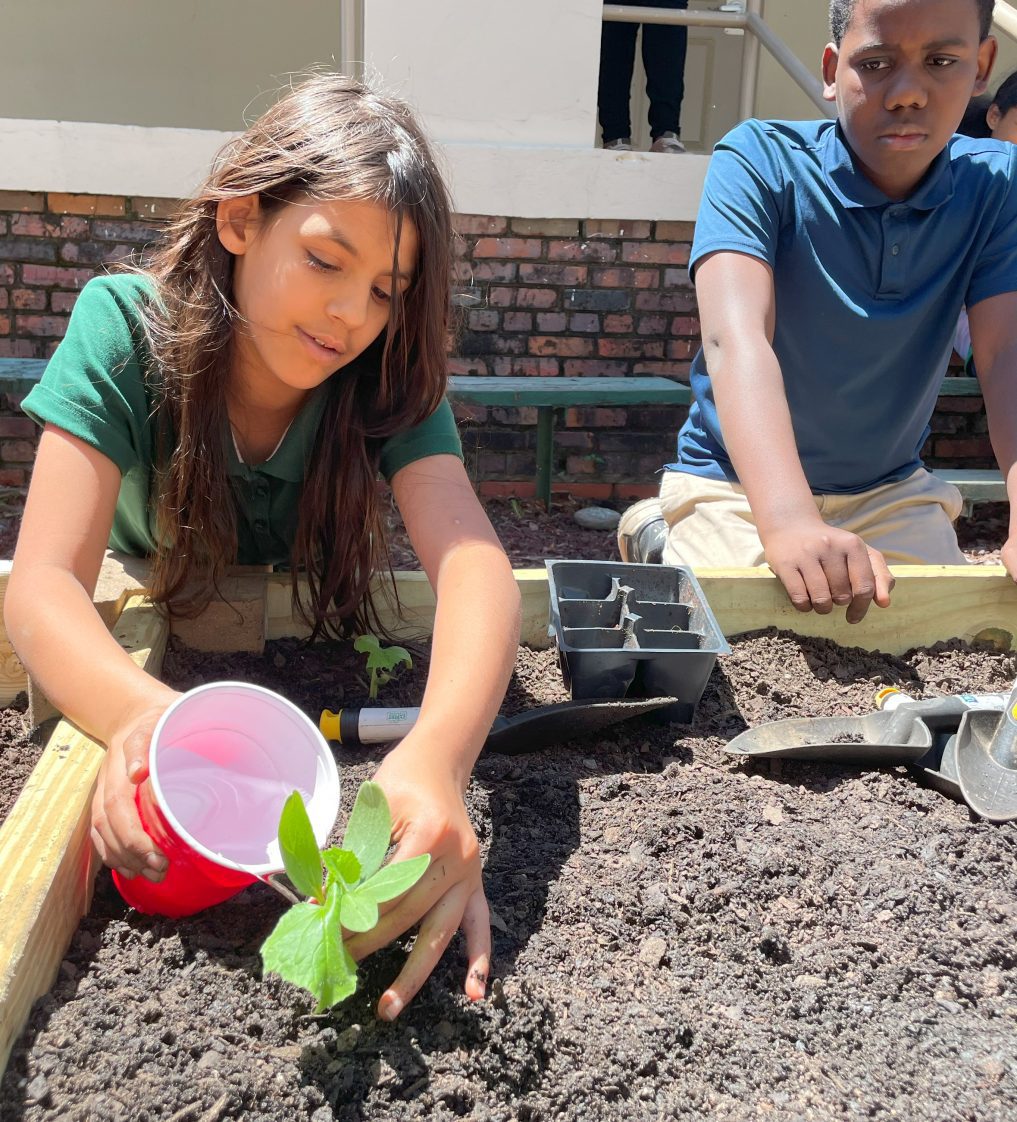 Two young people planting in a raised bed.