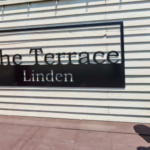 Two women pose for a photo with a sign that reads The Terrace Linden.