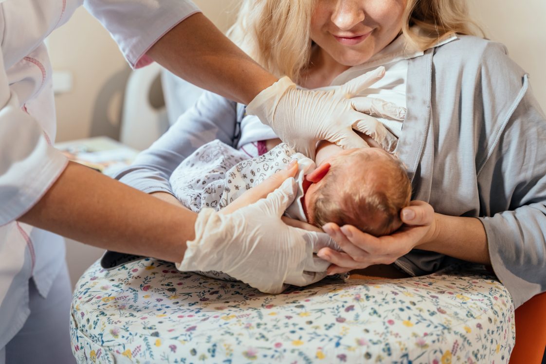 A nurse helping a mom and her baby breastfeed in a hospital.