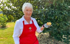 Master Gardener, Jean Szabo, holds a pear grown in their garden at the Crump Community Center.