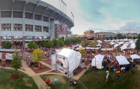 A picture of the outside of Auburn University's Jordan-Hare Stadium with people tailgating under white tents.