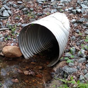 Figure 4. Permanent forest road culvert. Correct: Installed at gradient level for fish and aquatic organism passage and utilizing rip-rap (large rock) to stabilize the fill material.