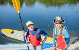 Portrait of two kids enjoying kayak ride on beautiful river.