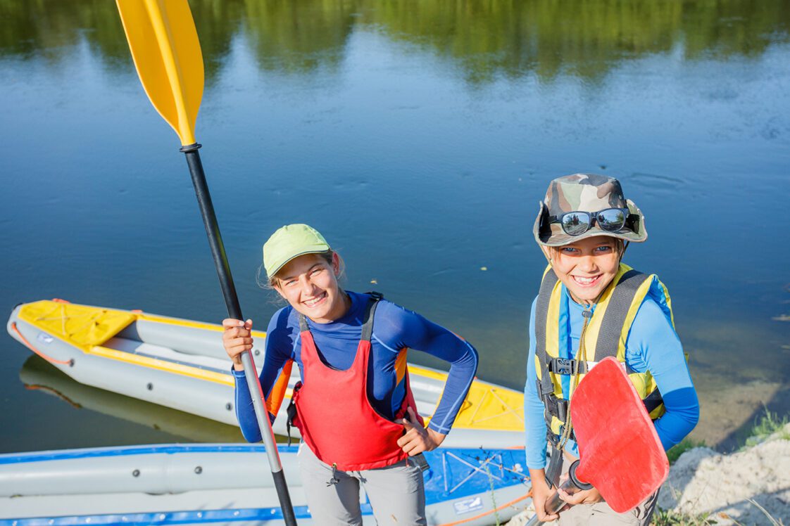 Portrait of two kids enjoying kayak ride on beautiful river.