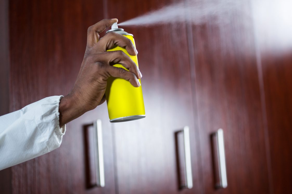 A person spraying an aerosol spray indoors.