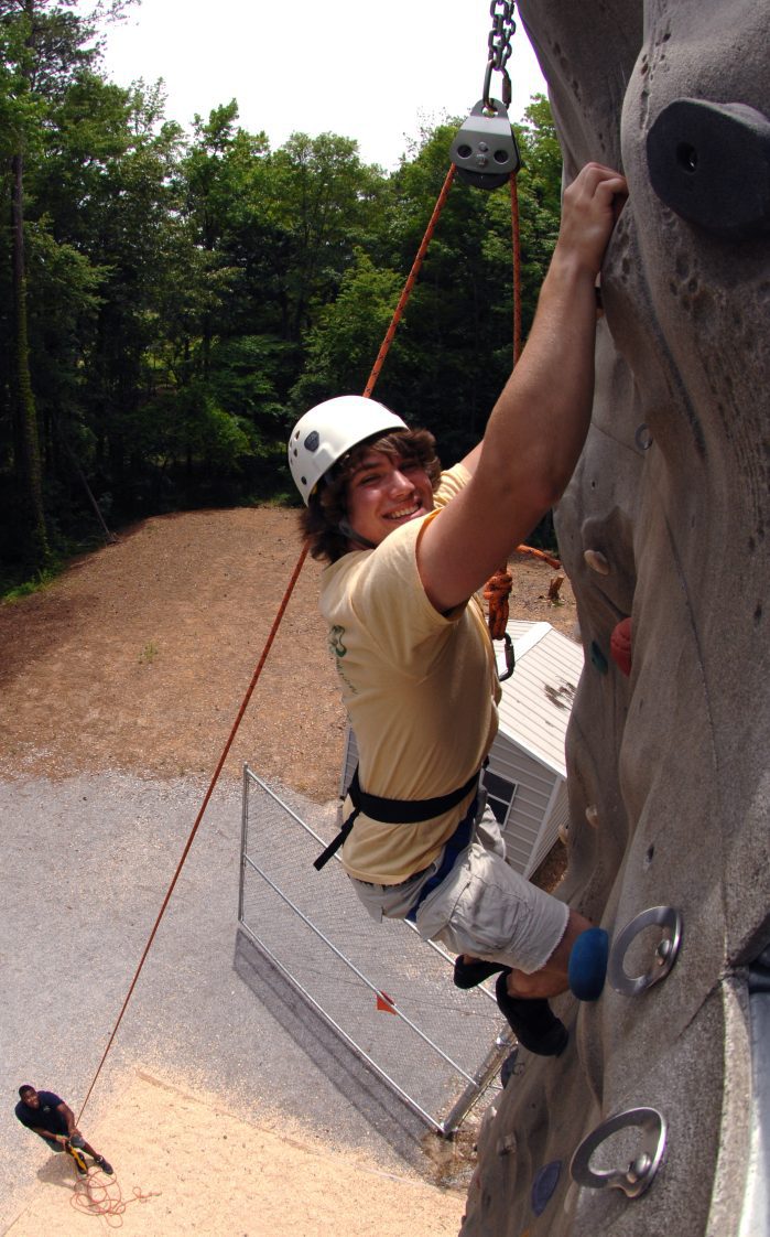 A 4-H member climbing the rock wall at summer camp