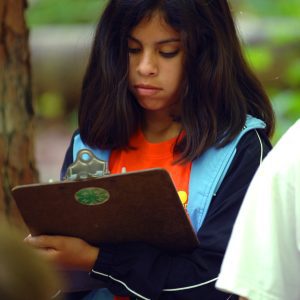A young girl 4-H member holding a clip board at summer camp