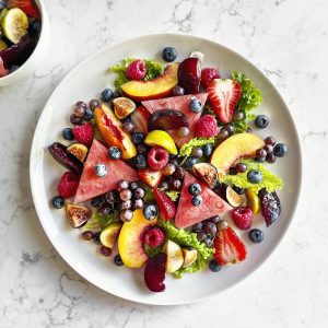 Plate of fruit salad on white, marble background