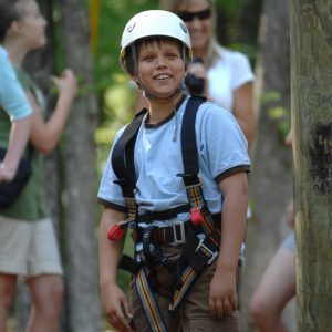 A young boy 4-H member wearing a harness before riding the big swing at summer camp.
