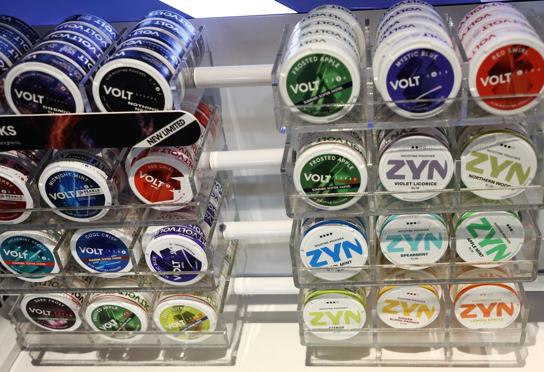 Several different brands of nicotine pouches on a shelf.
