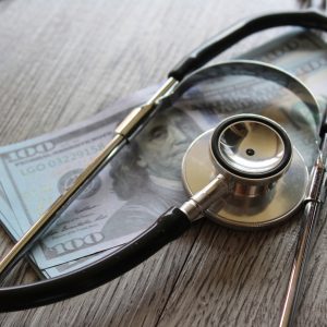 Stethoscope and money on wooden table