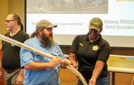 Snake Expert Jimmy Stiles helps a first responder examine a rattlesnake.