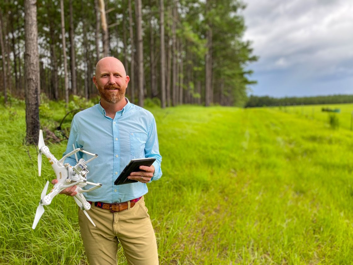 Beau Brodbeck standing with a drone in a field.
