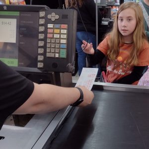 A child paying for vegetables with a voucher at Piggly Wiggly