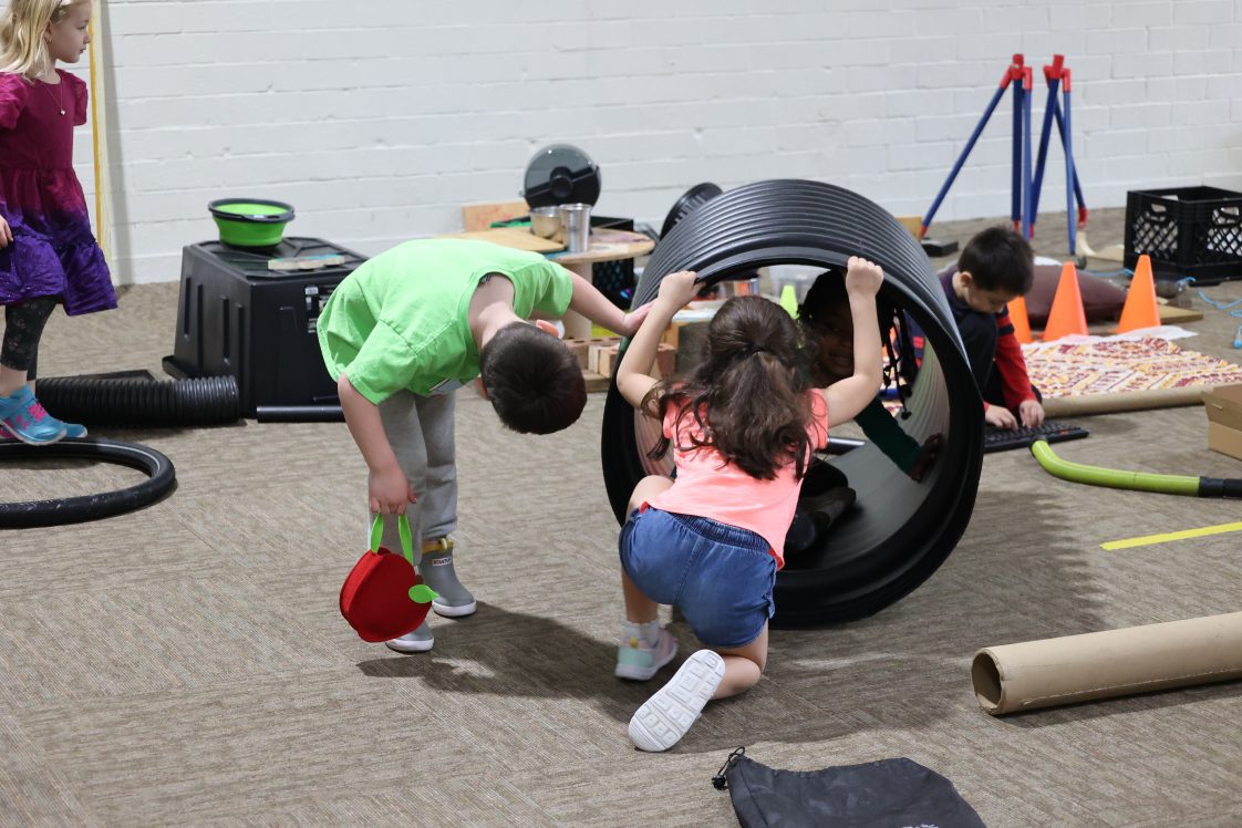 Two children at a day care playing in a loose parts playground.