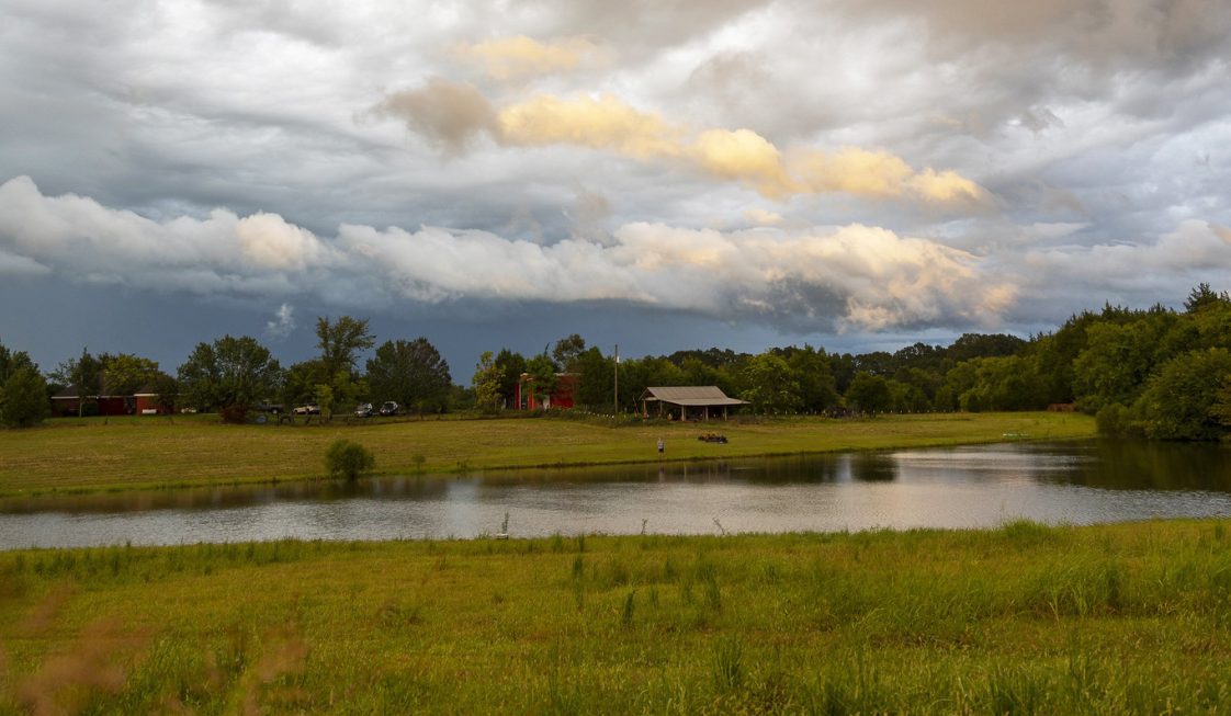 A farm scene with a barn and pond