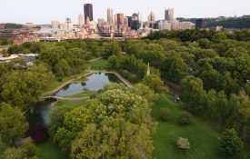 A drone shot of an urban/city park with ponds and tree coverage.
