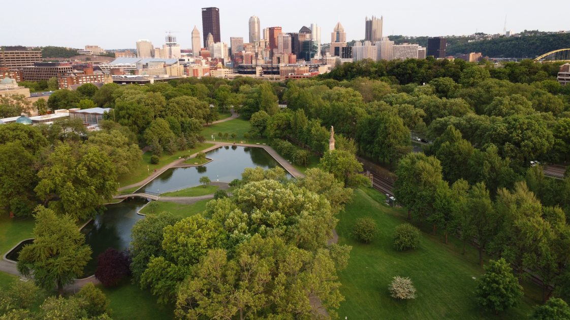 A drone shot of an urban/city park with ponds and tree coverage.