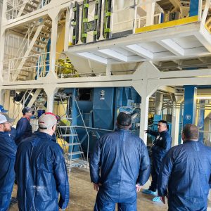 A group of people in blue smocks touring a facility.