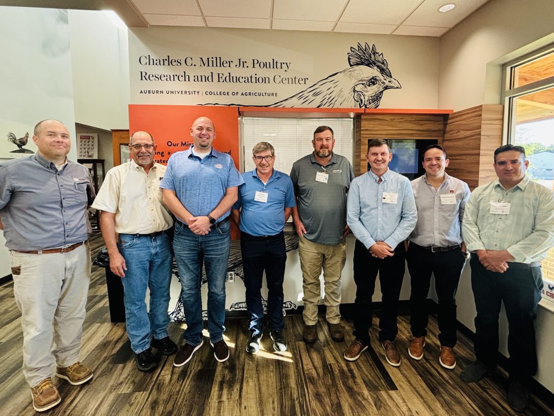 A group of men standing inside the Charles C. Miller Jr. Poultry Research and Education Center.