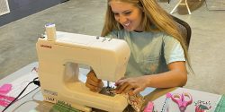 A 4-H member sitting at a sewing machine.