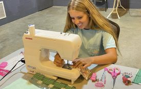 A 4-H member sitting at a sewing machine.