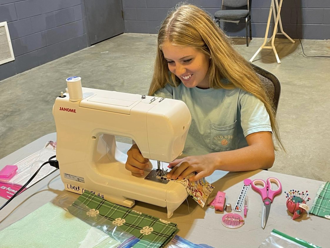 A 4-H member sitting at a sewing machine.