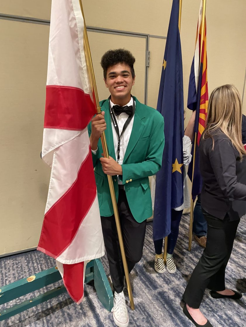 A 4-H Ambassador holding the state flag of Alabama.