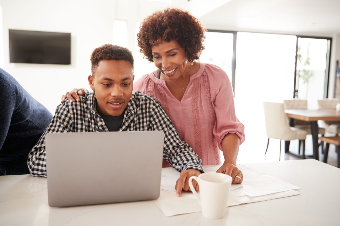 A Black mother and her son looking at a laptop.