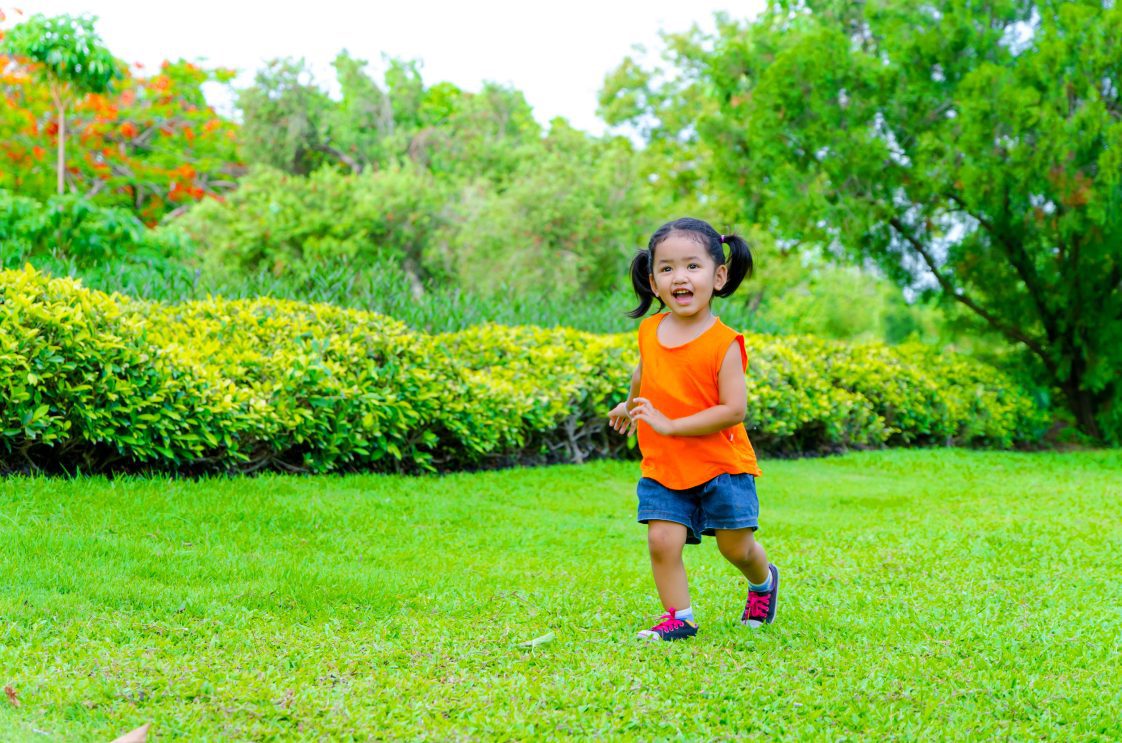 A young Asian girl running through the yard.