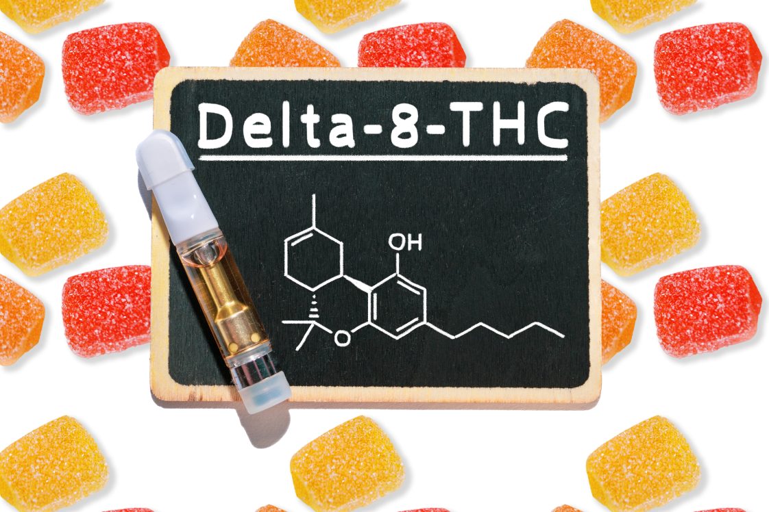 Gummy candies on a white background with a chalkboard that has the words "Delta-8-THC" written on it.
