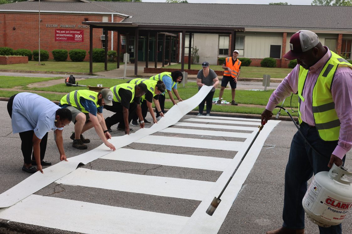 A group of people installing a crosswalk at Eutaw Primary School in Greene County, Alabama.