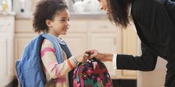 Mixed race mother handing lunch box to daughter