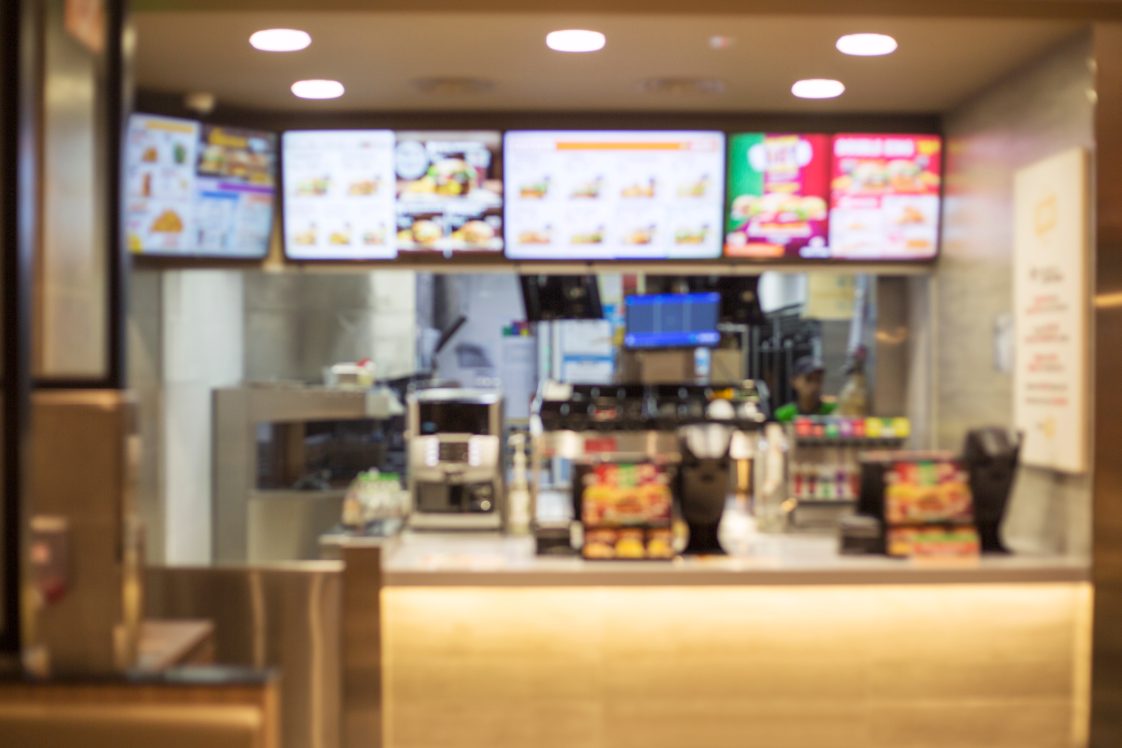 A blurred image of a fast-food restaurant counter and menu board.