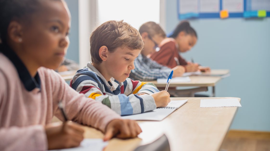 Four middle school students sitting on the front row of a classroom.