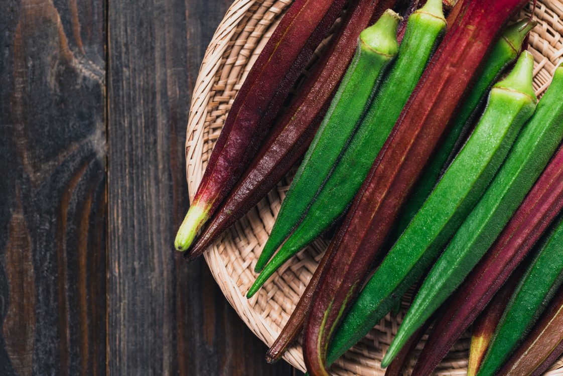 Green and red okra or ladies' fingers in basket on wooden, Organic vegetables from local farmer market