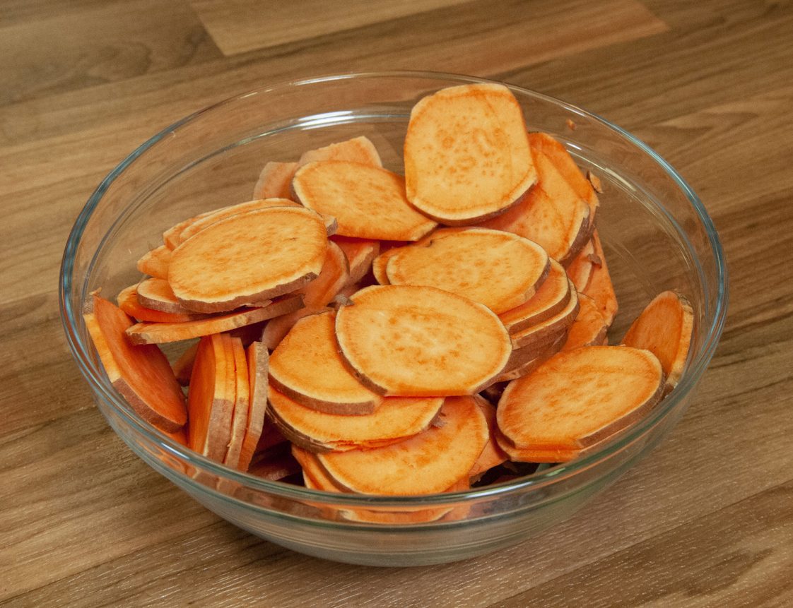 A glass bowl of sliced sweet potatoes
