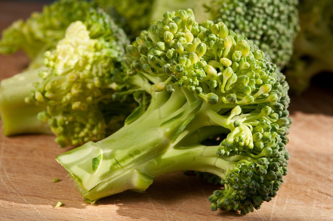 Cut broccoli sitting on a wooden cutting board.