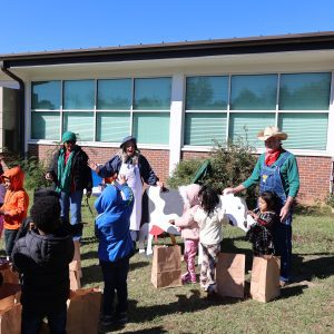 A group of children listening to adults talk about dairy cows at the Farmers Walk event.
