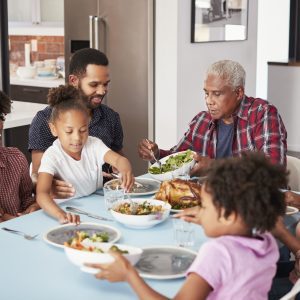 Multi Generation Family Enjoying Meal Around Table At Home