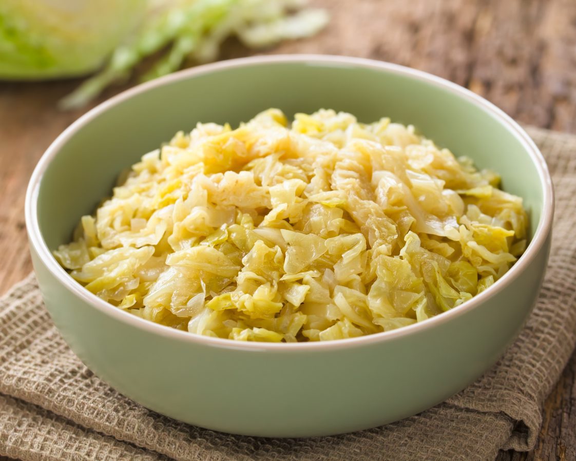 Fresh homemade braised white cabbage in bowl, raw cabbage in the back (Selective Focus, Focus one third into the cabbage)