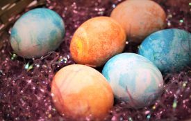 Dyed Easter eggs in a basket of fake grass.