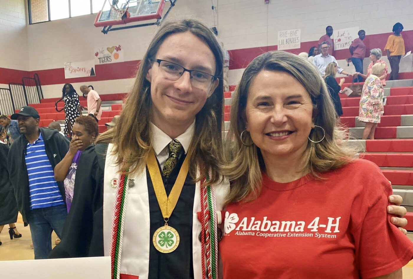 A high school student and 4-H member at graduation posed for a picture with his 4-H agent. 